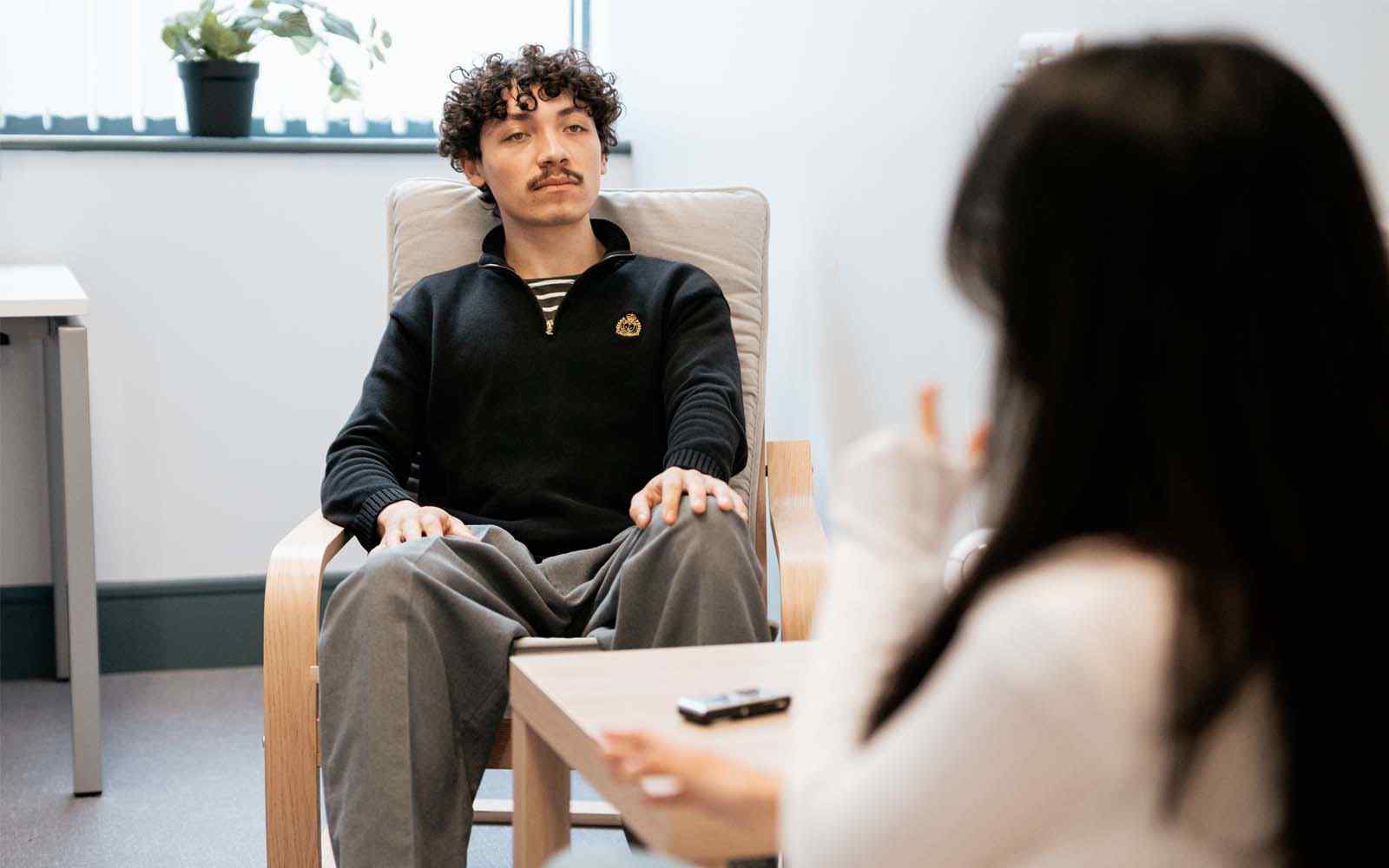 Dark haired male sitting across from female psychologist