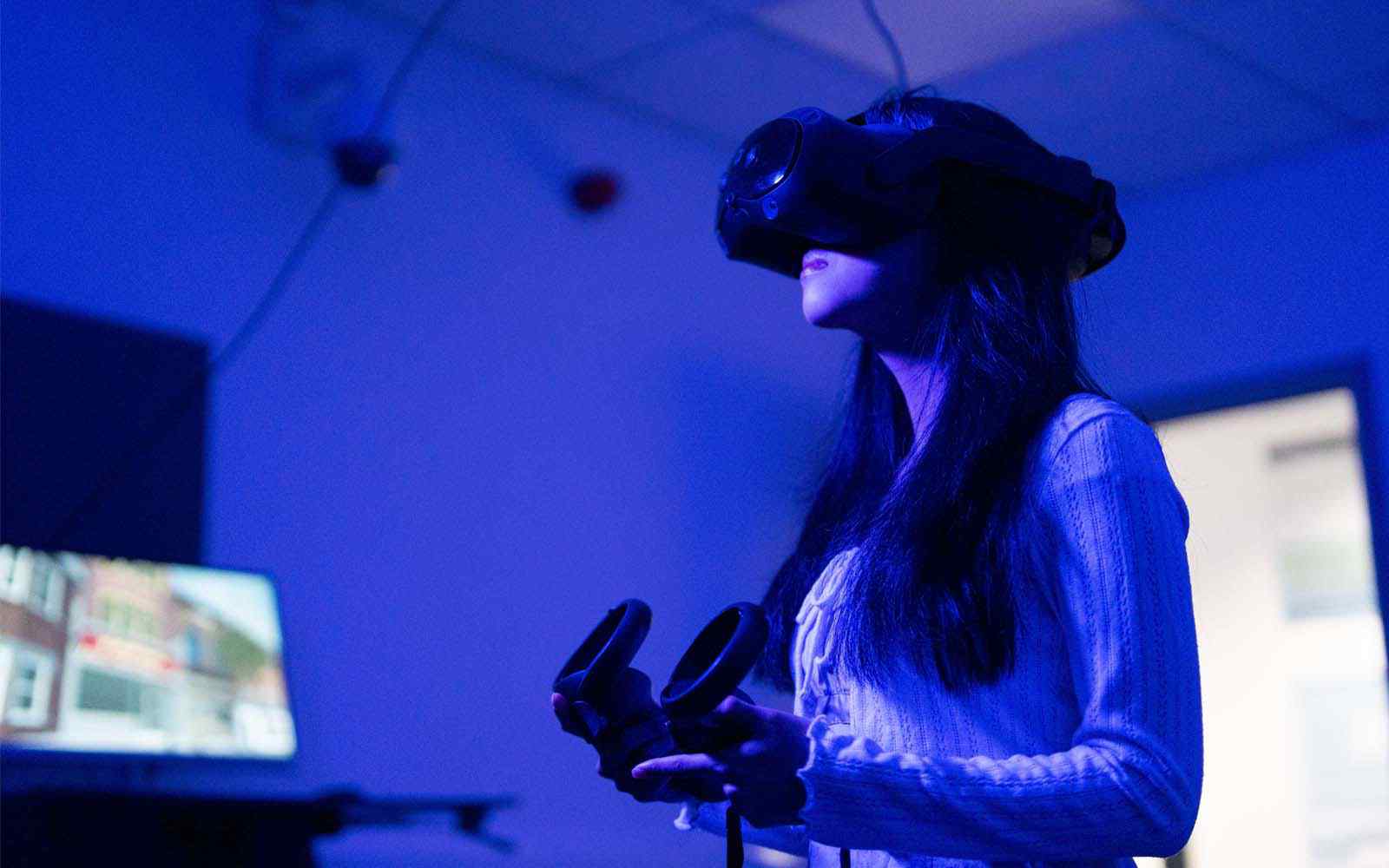 Female student using Virtual Reality system in dark room
