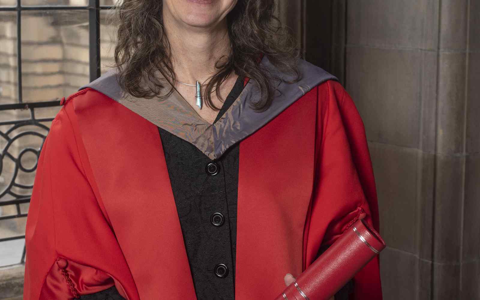 Alison Phipps in a red graduation robe smiling at the camera