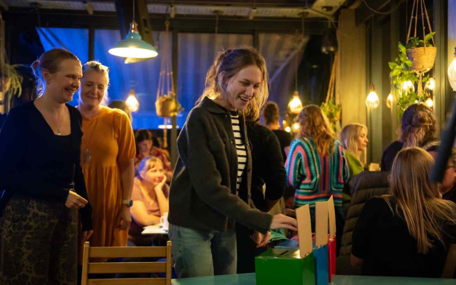People at a Living Lab event, sitting around tables and casting their votes into a box.