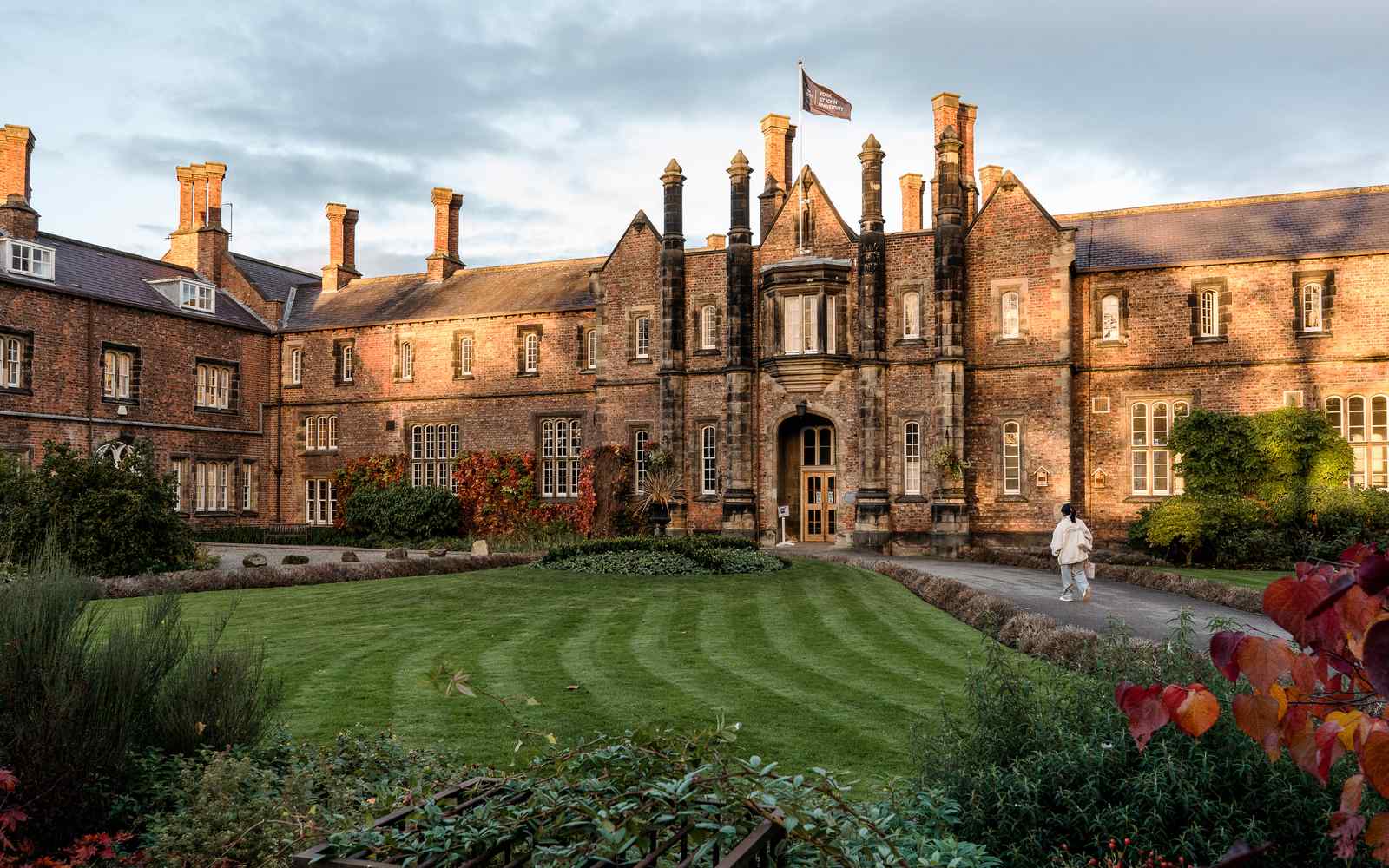 Photograph of university entrance surrounded by autumnal foliage.