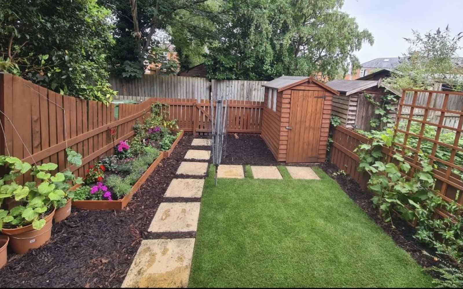 A back garden with a lawn and flower beds 