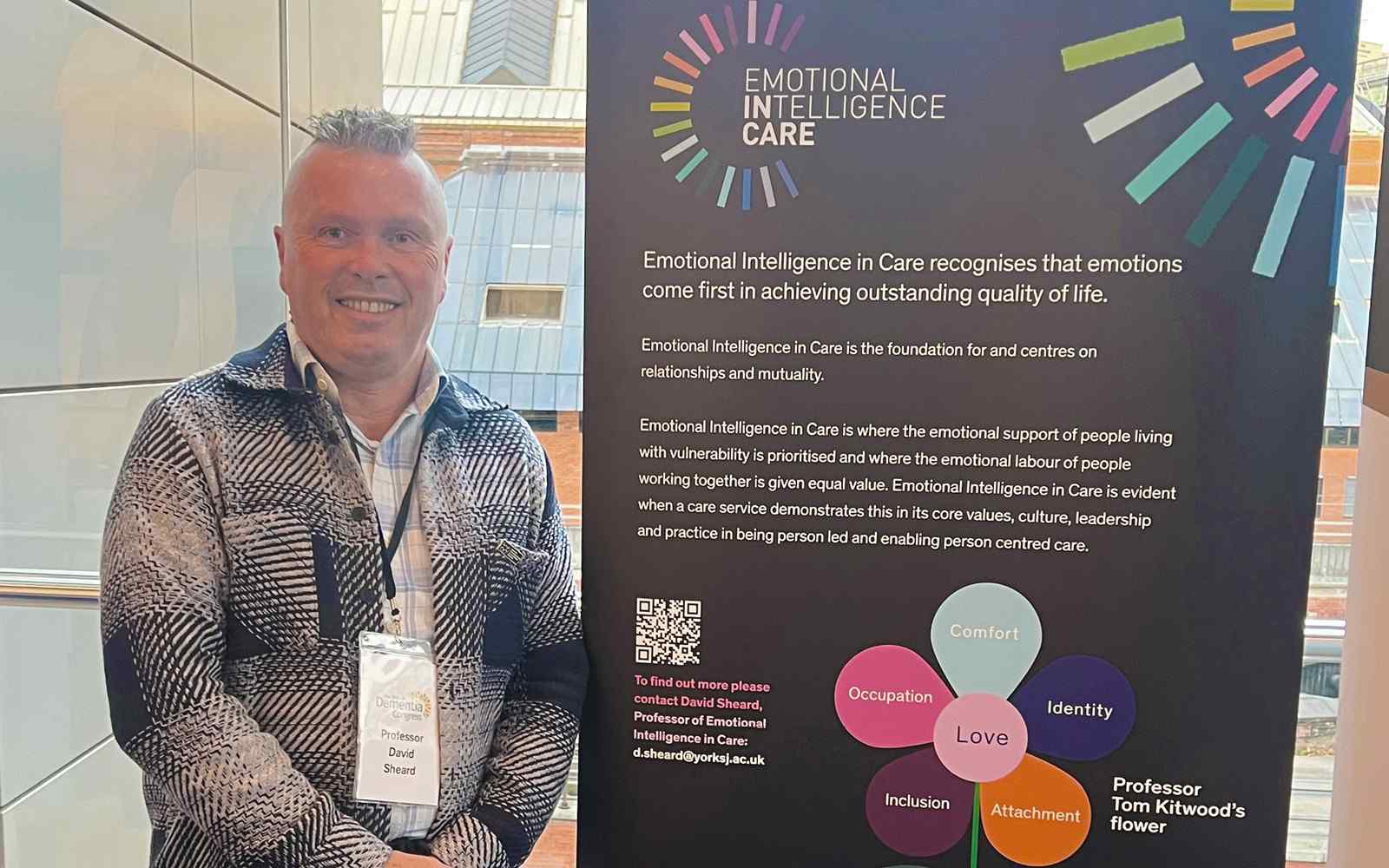 A male stood next to a banner which says Emotional Intelligence in Care