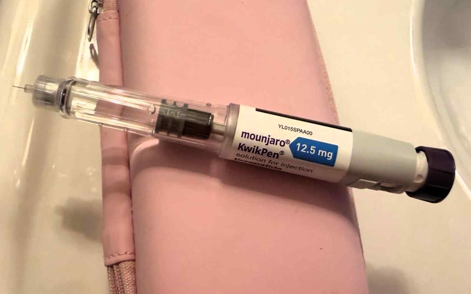 A close up image of a syringe of Mounjaro on the side of a bathroom wash basin