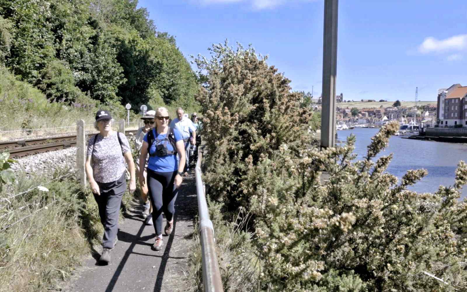 A group of walkers on a riverside path