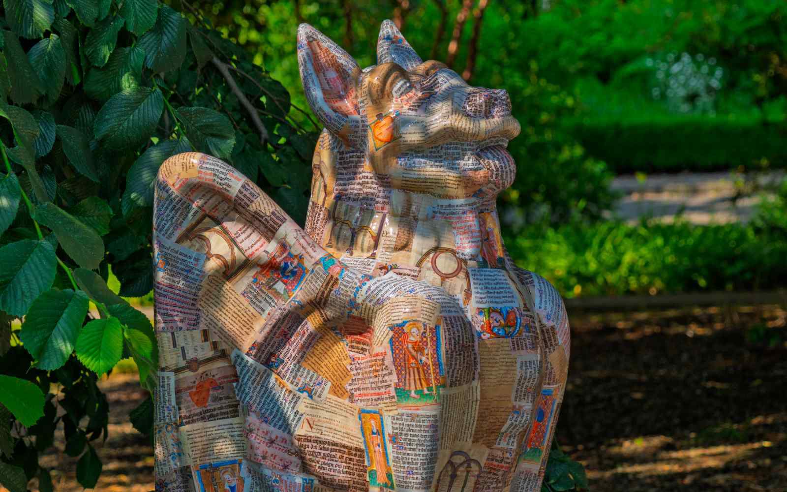 A gargoyle figure decorated with pages of illuminated manuscript
