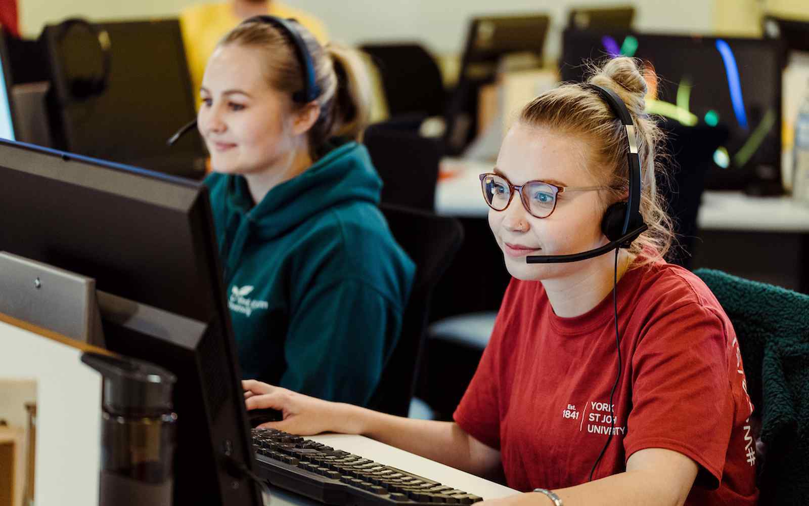 Two students sit before computer screens
