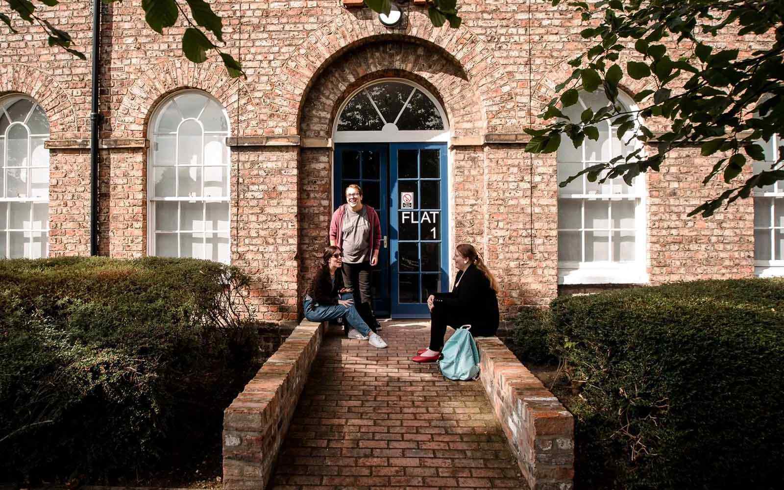 Three students chat outside The Grange accommodation.