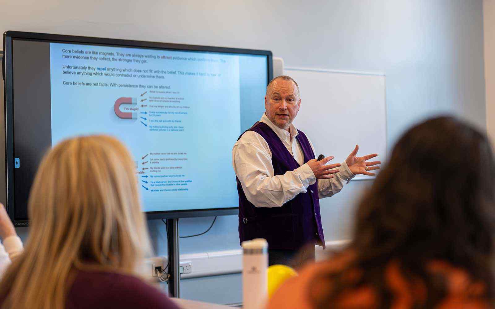 A lecturer teaching in front of a screen