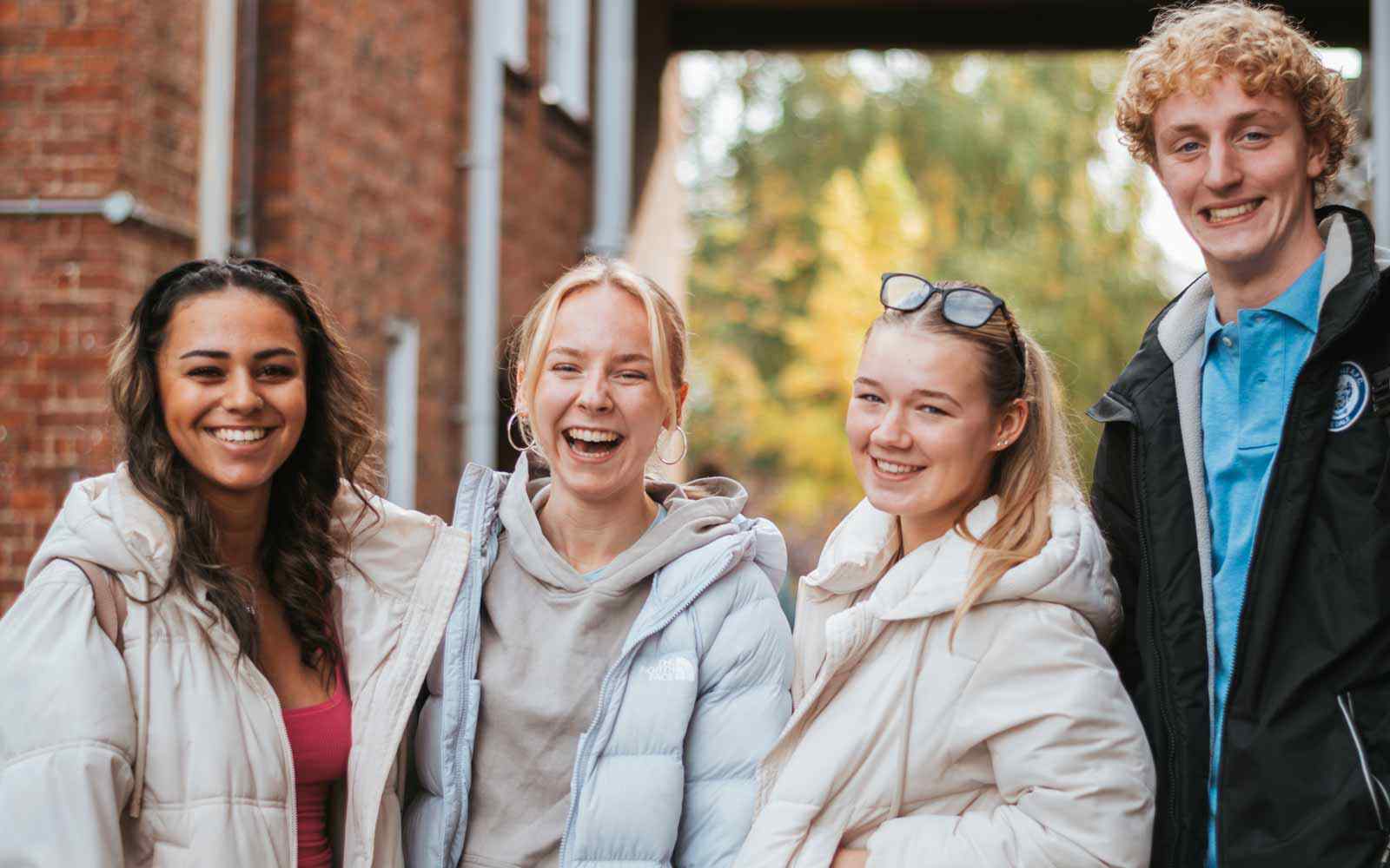 Students laughing and smiling outside on campus.