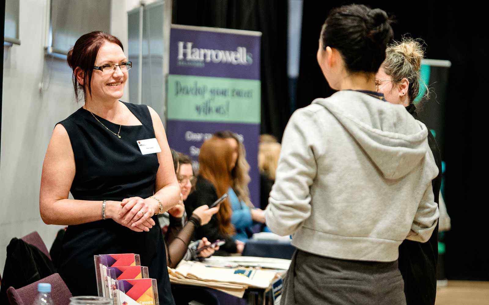 An employer speaking with students at a careers fair.