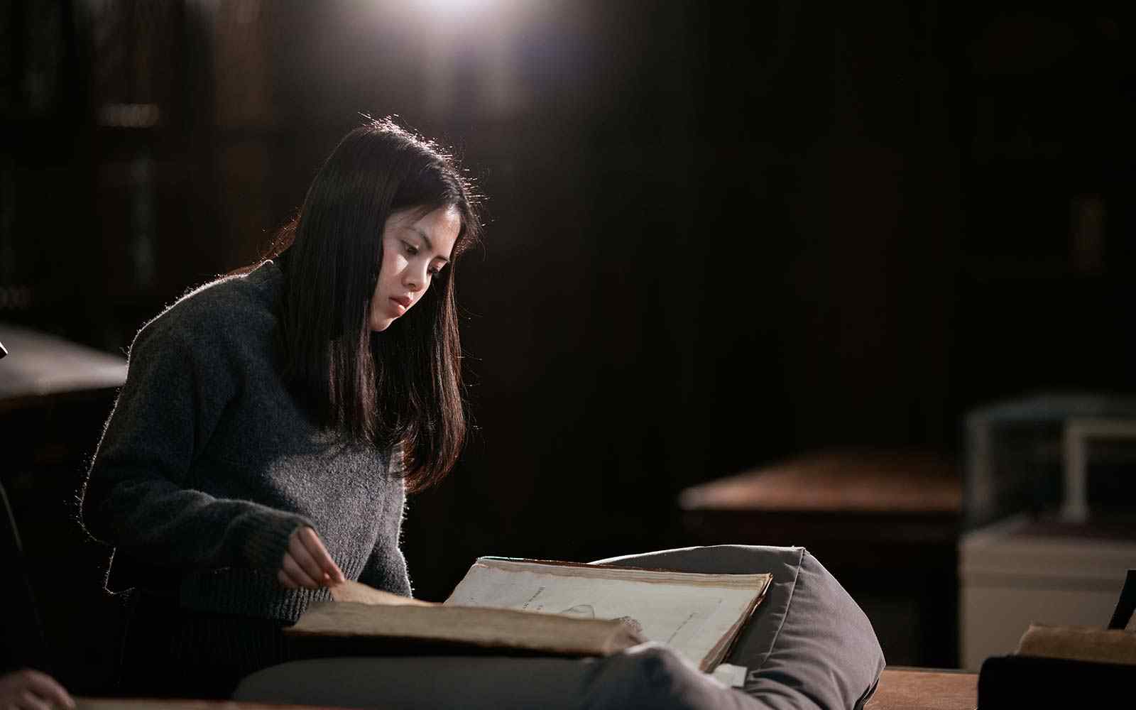 A student reads an old book in an archive setting.