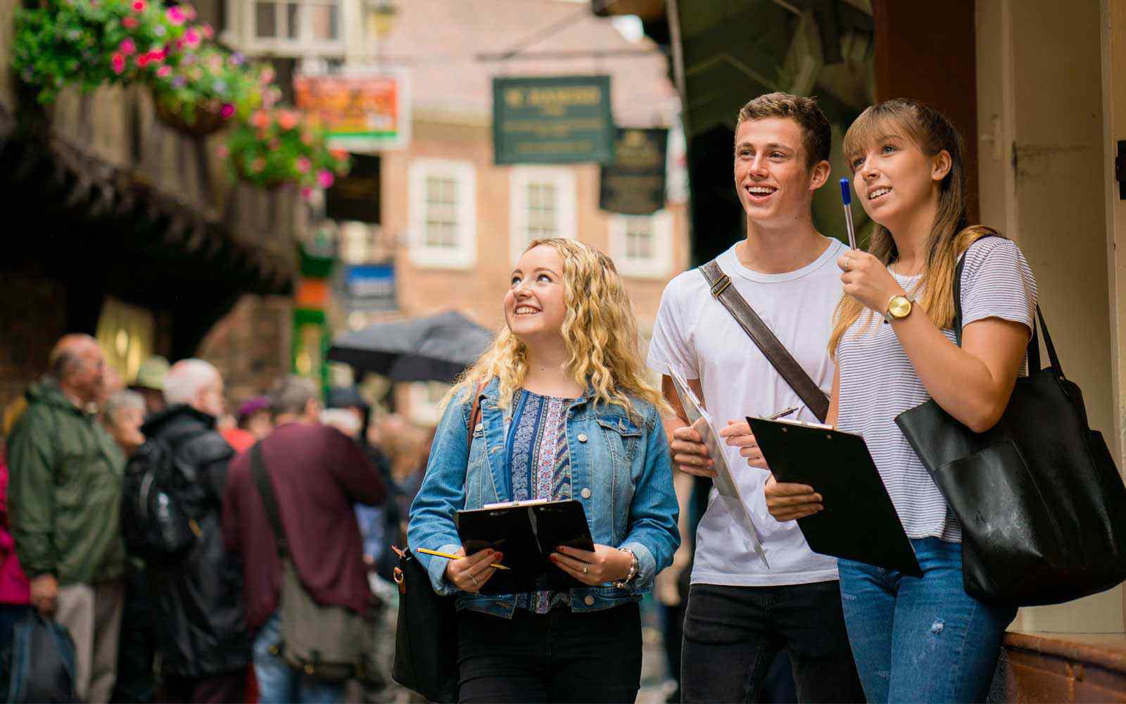 Students with clipboards looking at historic buildings on the Shambles in York city centre.