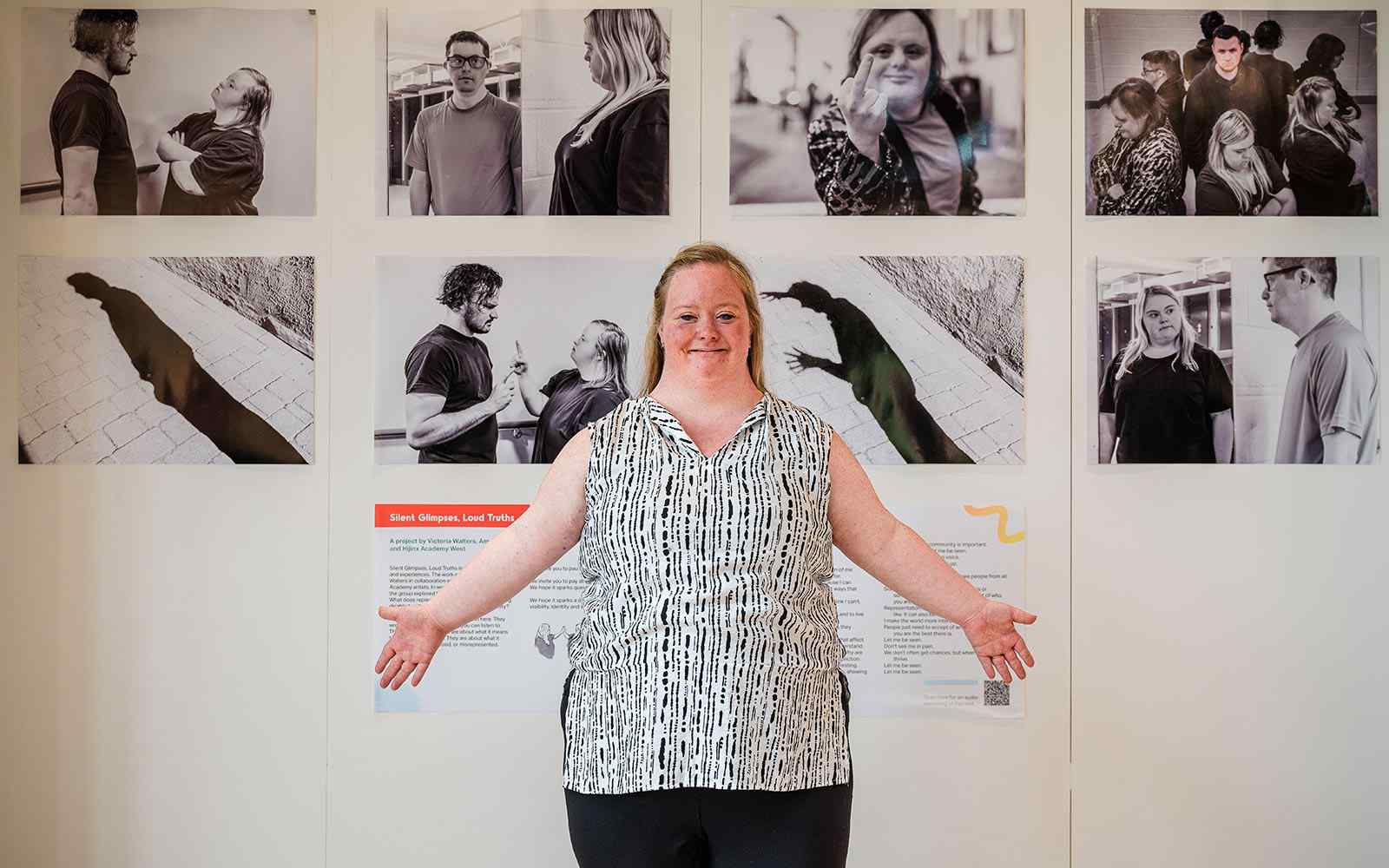 Person standing with arms out in front of photographs