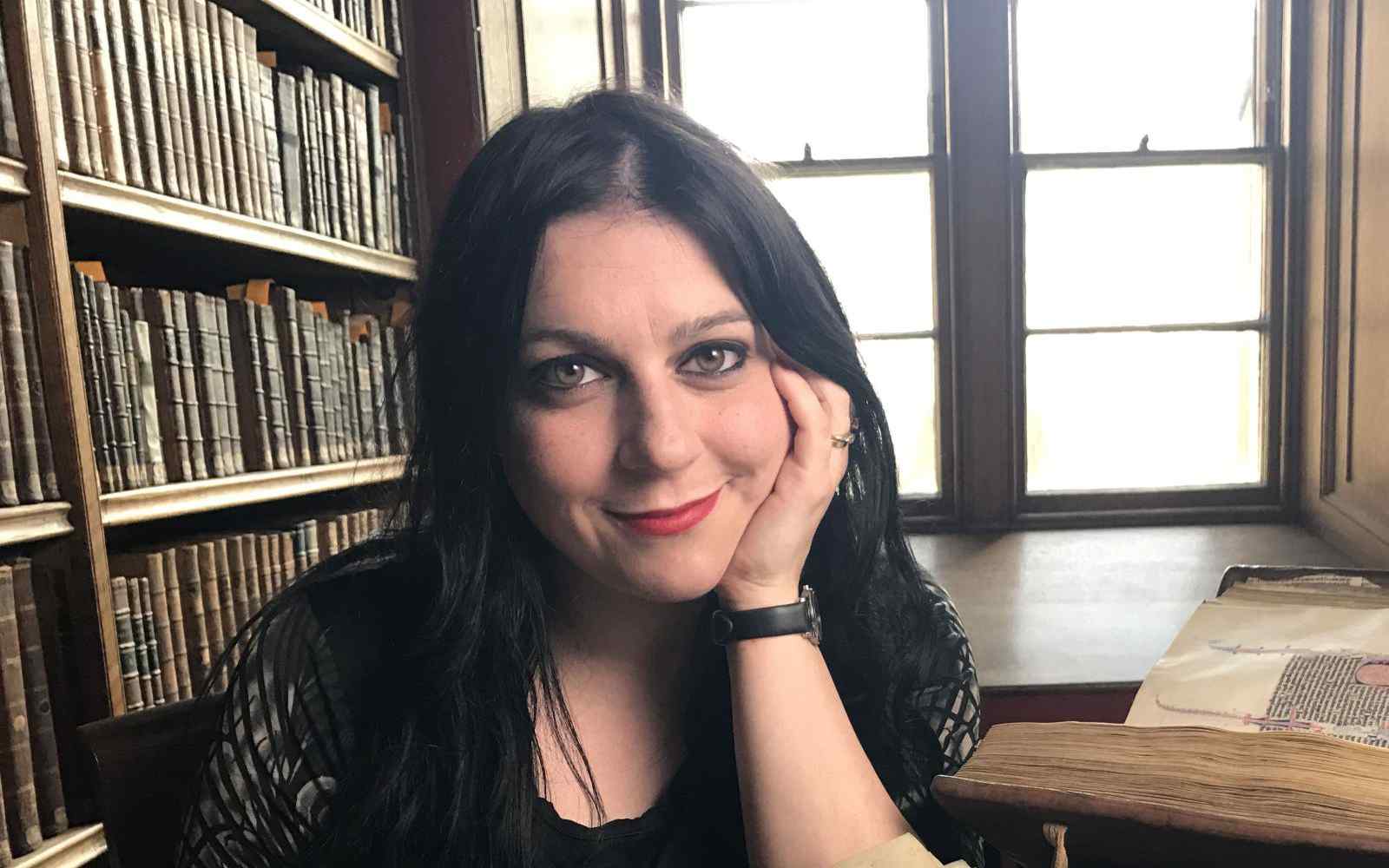 Janina Ramirez sitting portrait in front of a window and bookcase