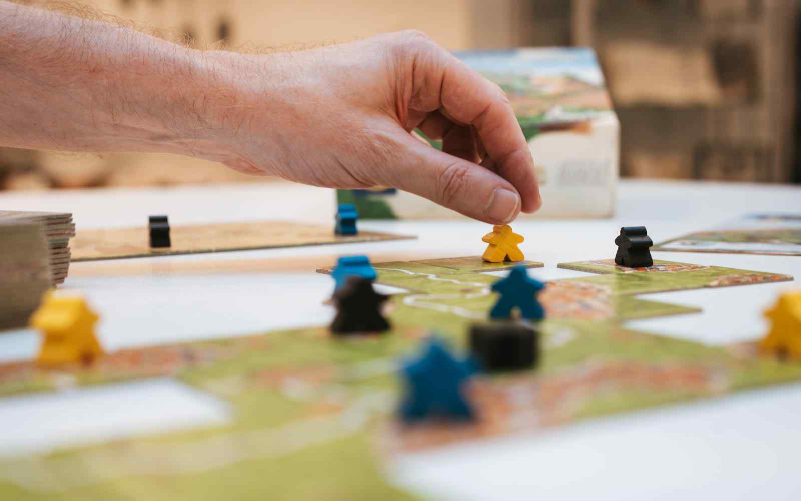 A student moving a piece in a game of Carcassonne.