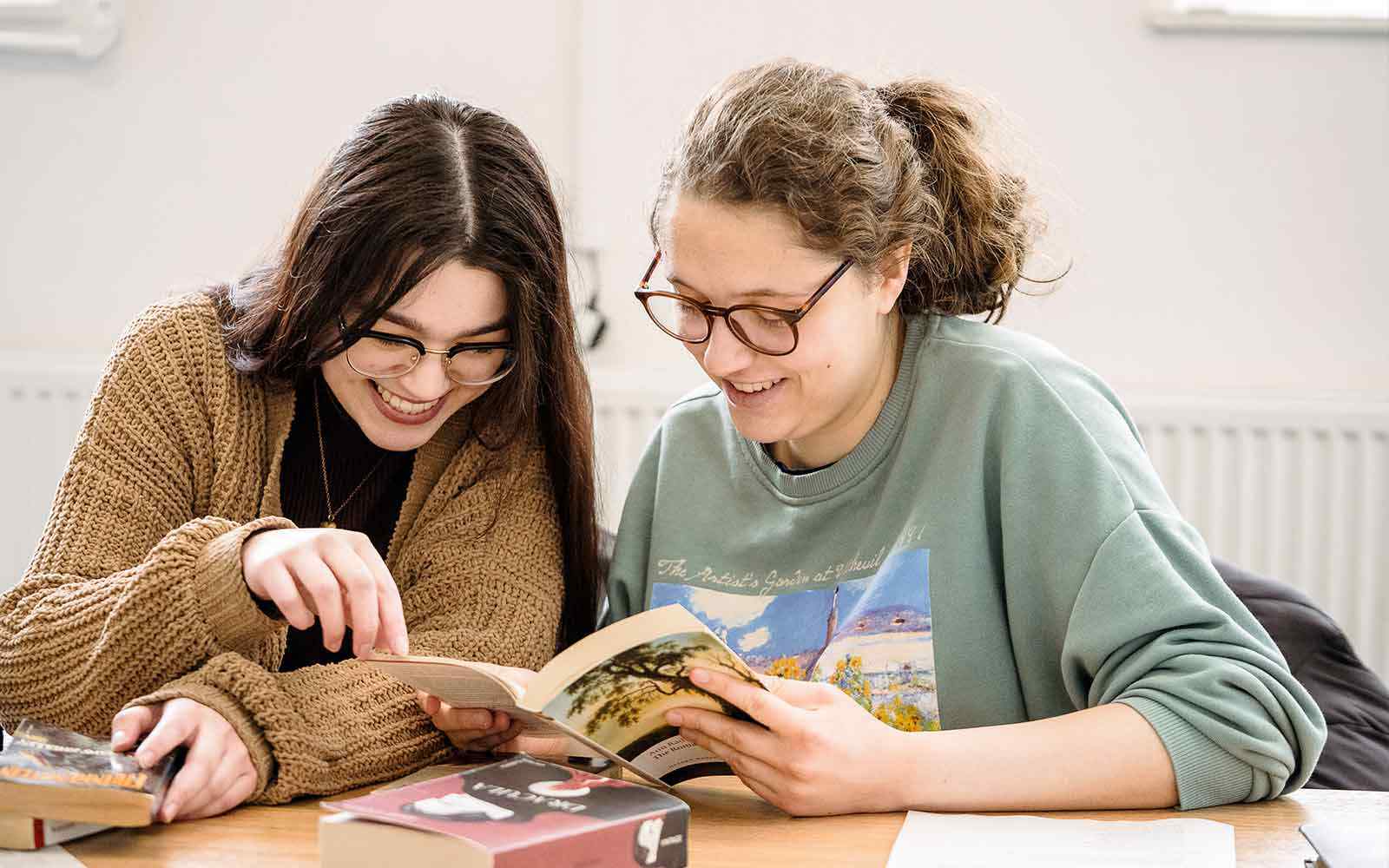 Two students reading through a book.