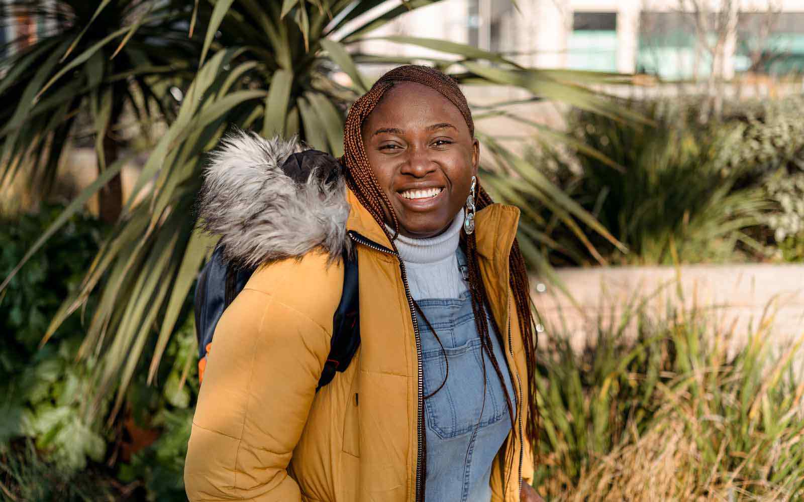 A student smiling and standing by a tree outside.