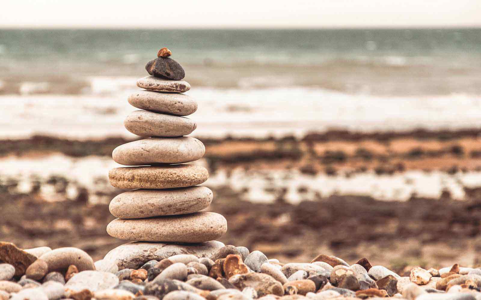 Tower of pebbles on a beach with the sea in the background.