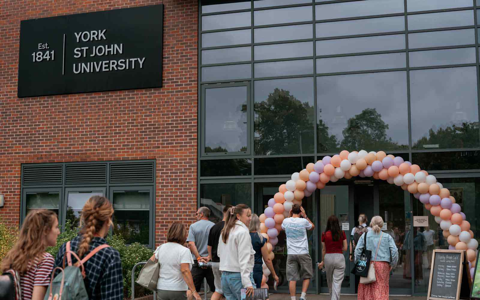 Visitors enter a campus building under a balloon arch at an Open Day event.