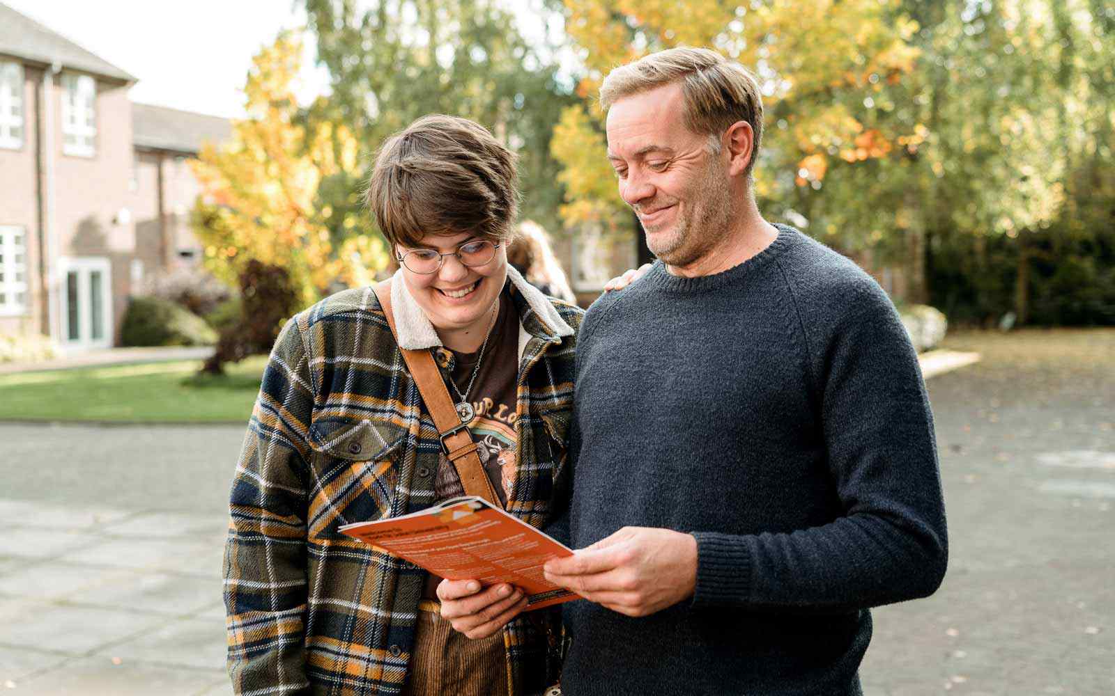 A parent and prospective student looking at a printed guide during an open day.
