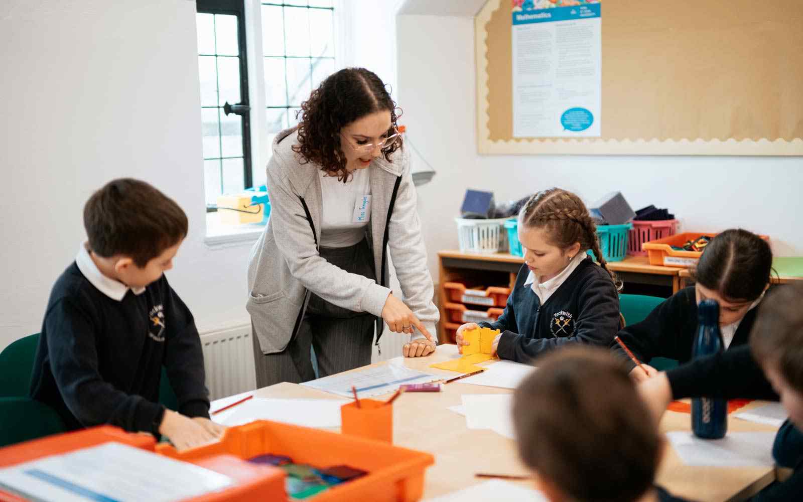 Female trainee teacher working with children in class.