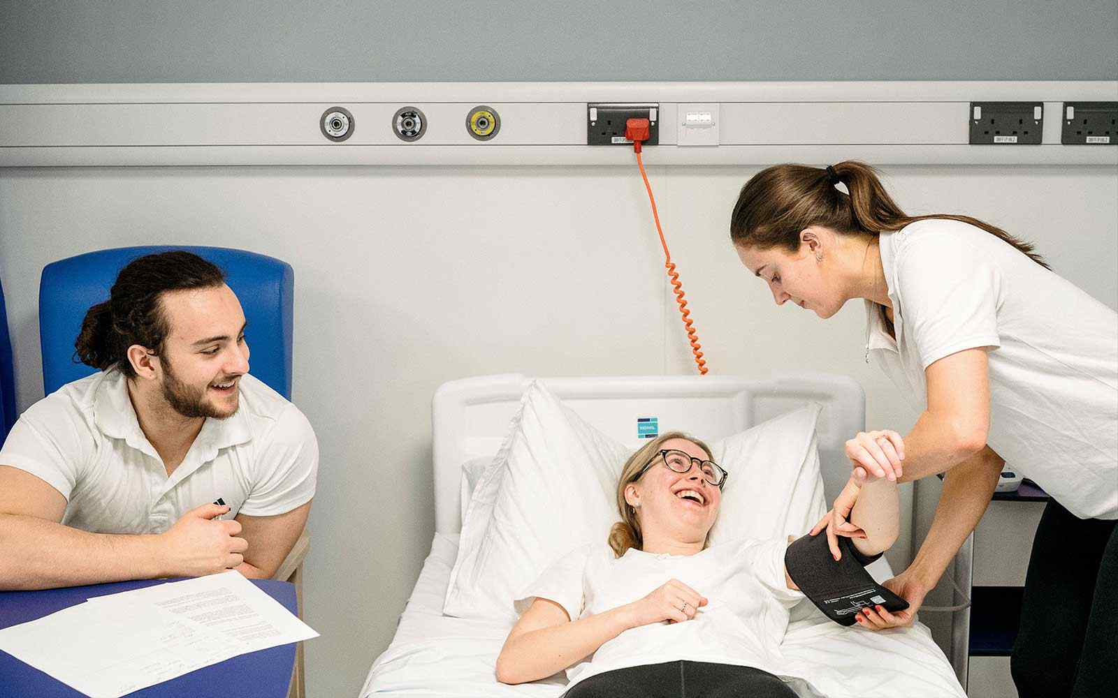 Three Physiotherapy students working in a ward setting.