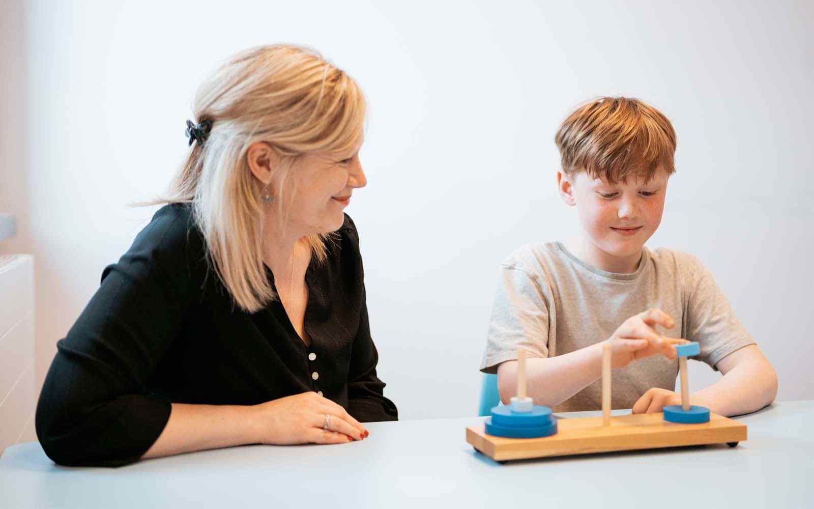 Psychologist and child sitting at table doing a stacking block game