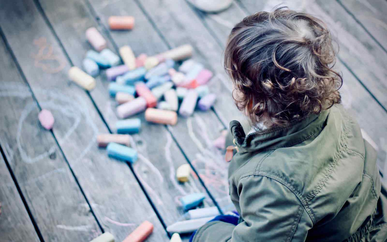 Child outside drawing with chalk
