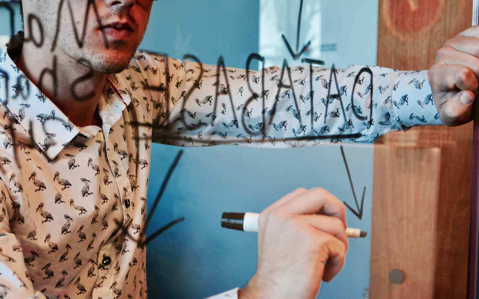Student writing ideas on glass with marker pen