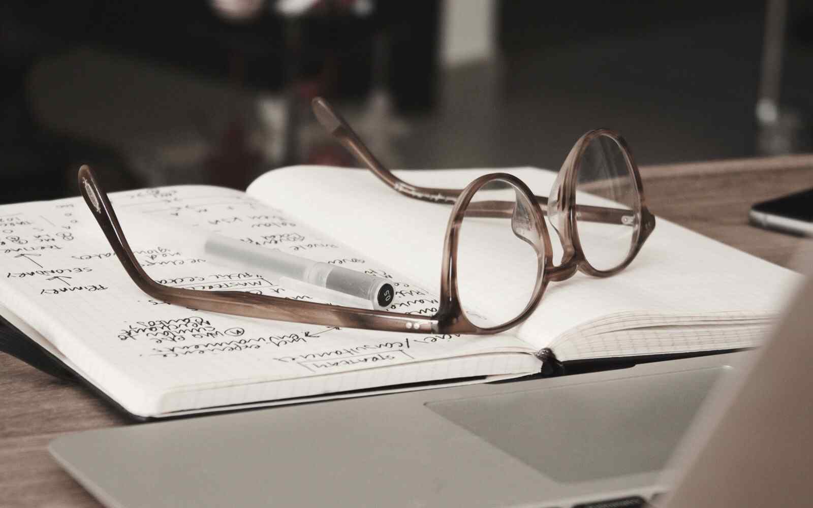 Open notebook with glasses on top.