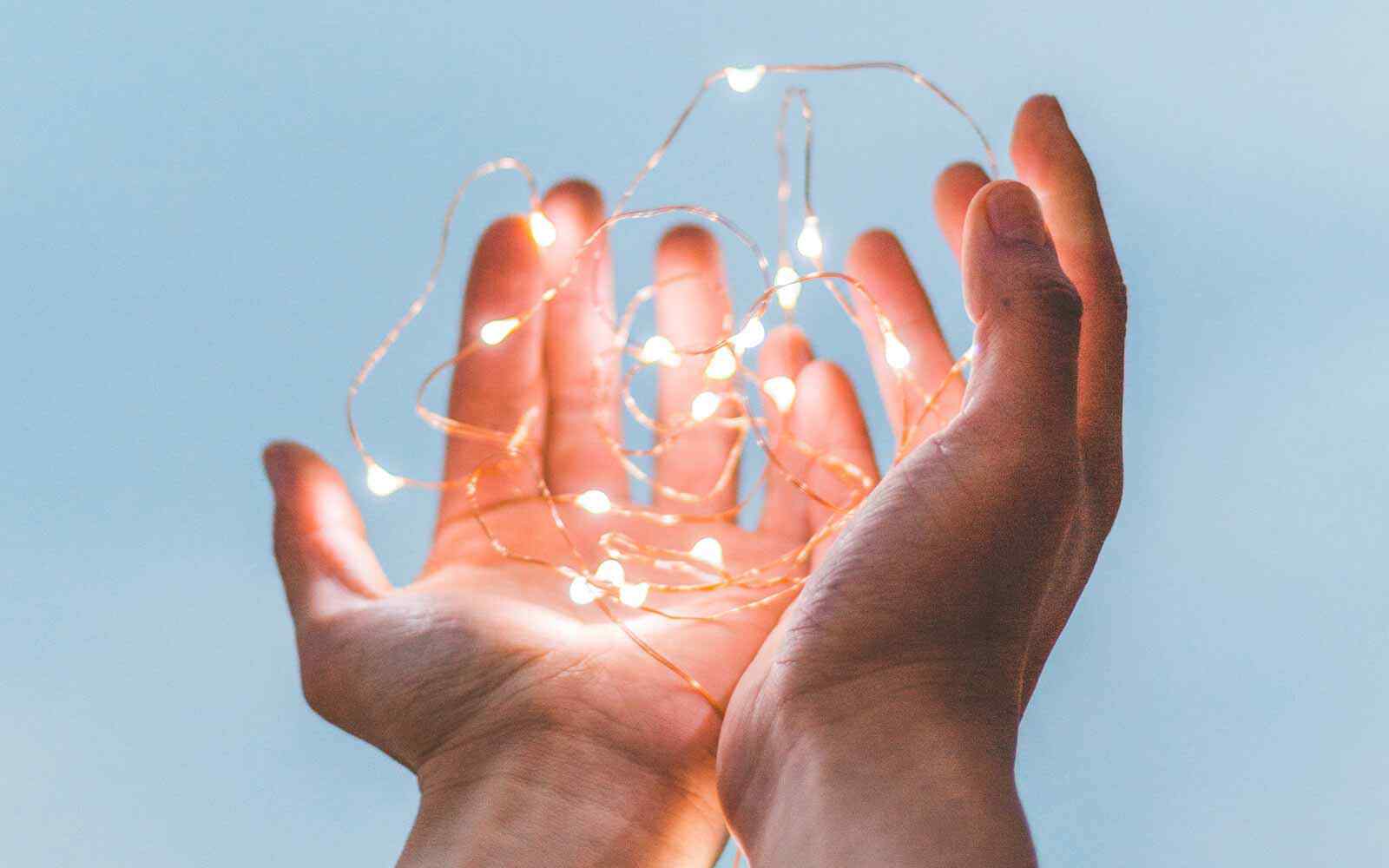 Hands with palms up, holding fairy lights.