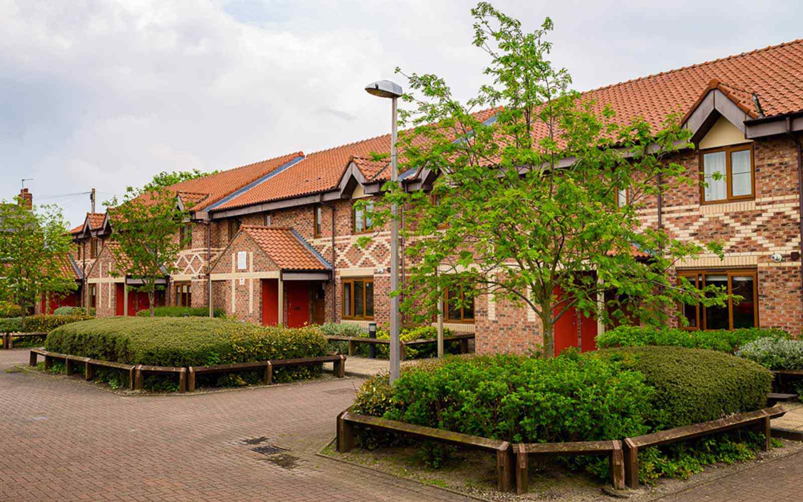 Exterior view of Limes Court accommodation; two-storey brick houses with bushes and trees outside.