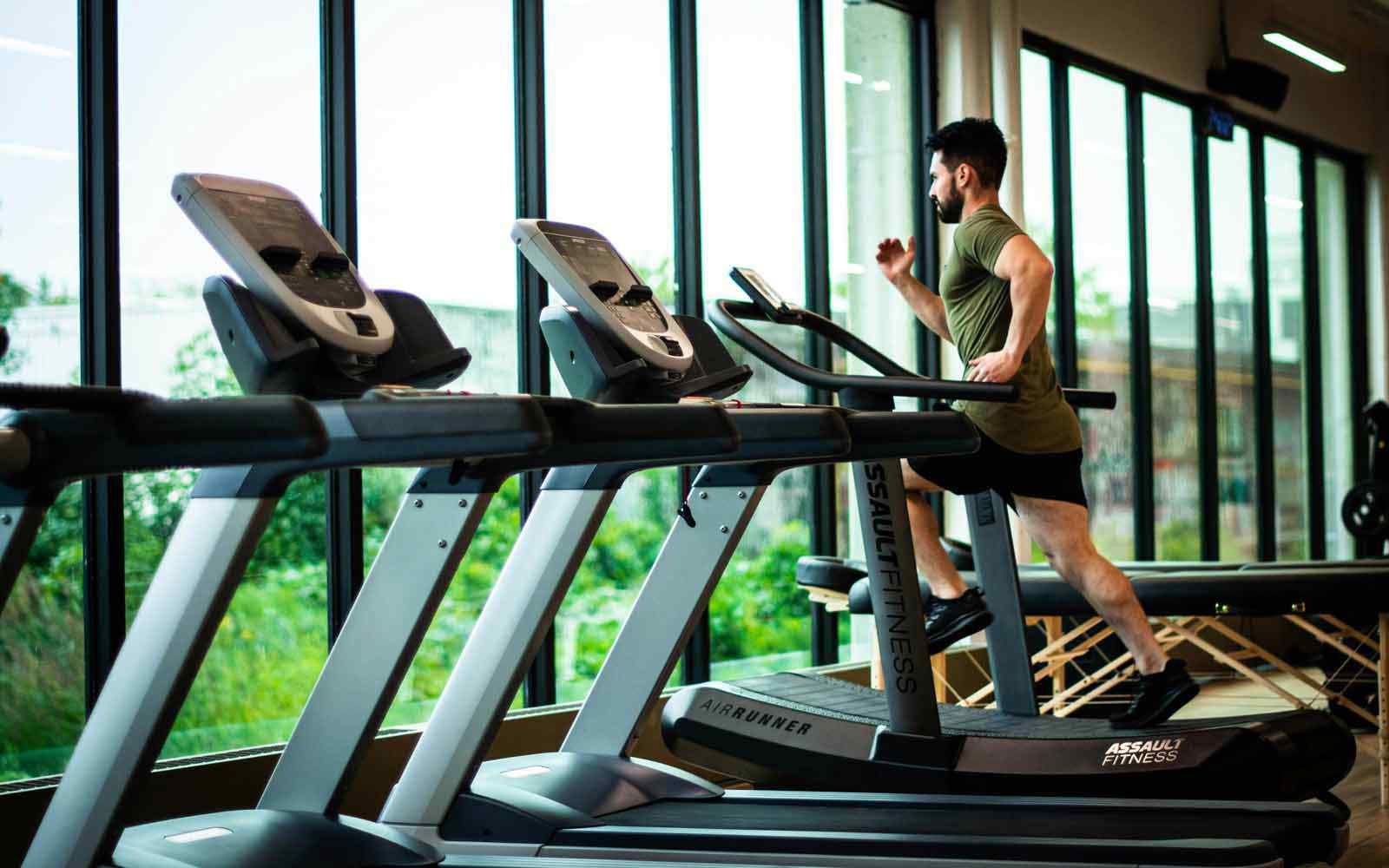 A man runs on a treadmill in a gym. Photo by William Choquette on Pexels.