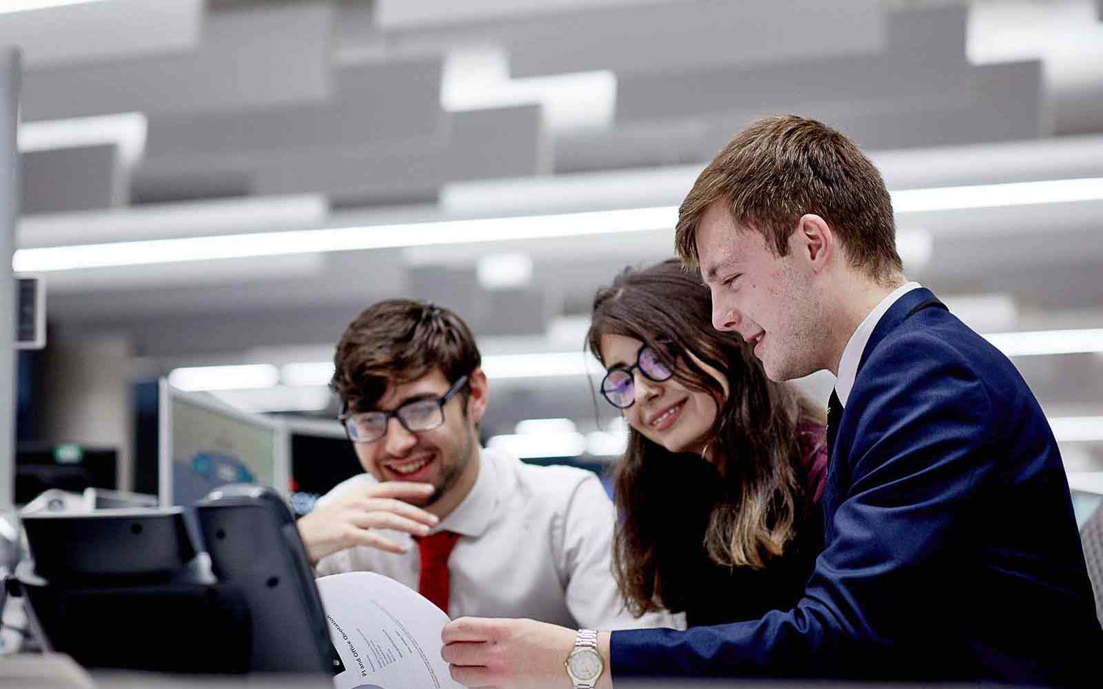 Three students work together at a laptop.