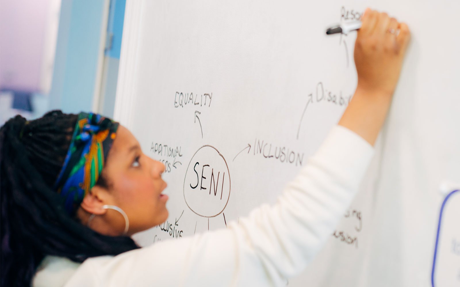 Student writing on a whiteboard in SENI classroom