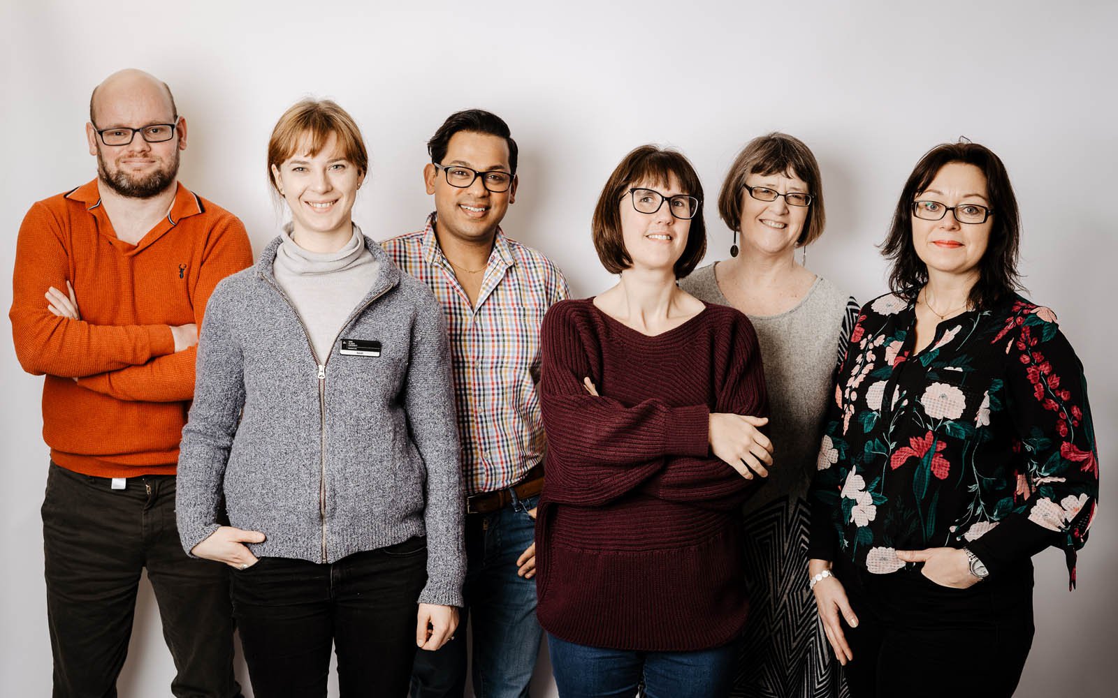 Group of York St John University staff in front of white background, smiling