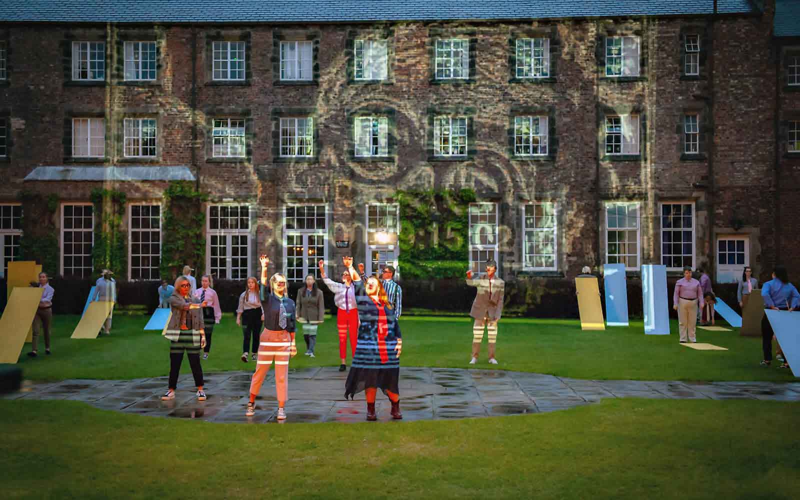 Outdoor performance in front of campus building with projected lights