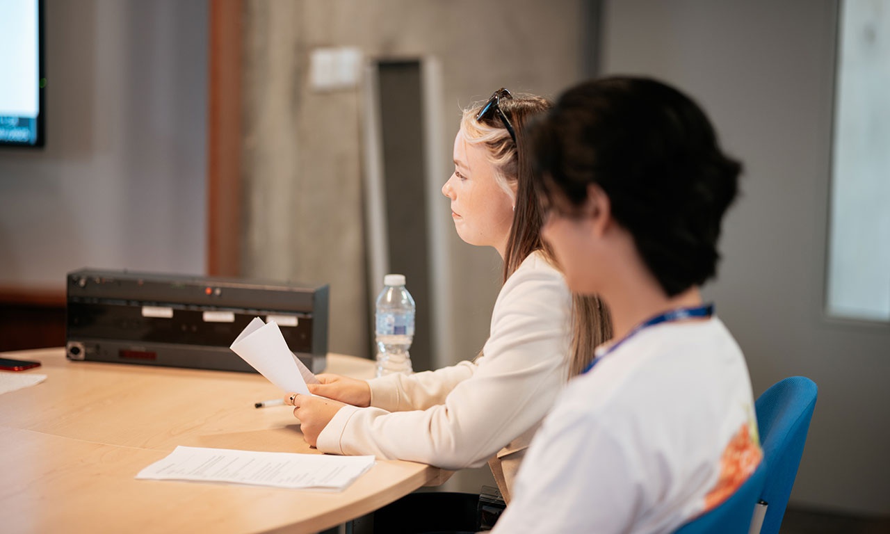 Students sat at desk with sheets of paper in front of them 