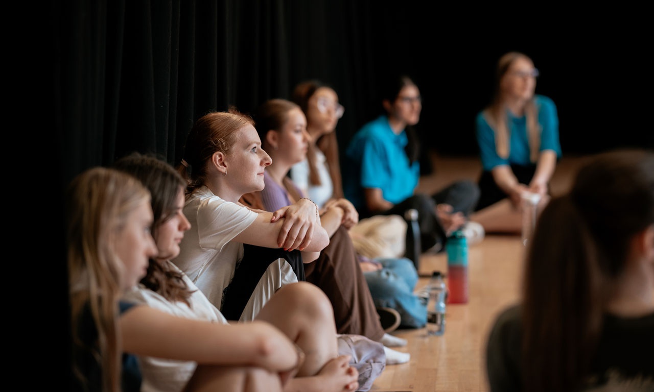 Students sat in line on floor in drama studio during workshop 