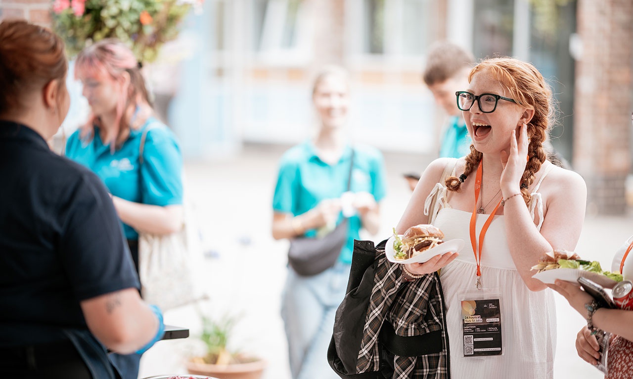 Happy student speaking to catering staff at barbecue 