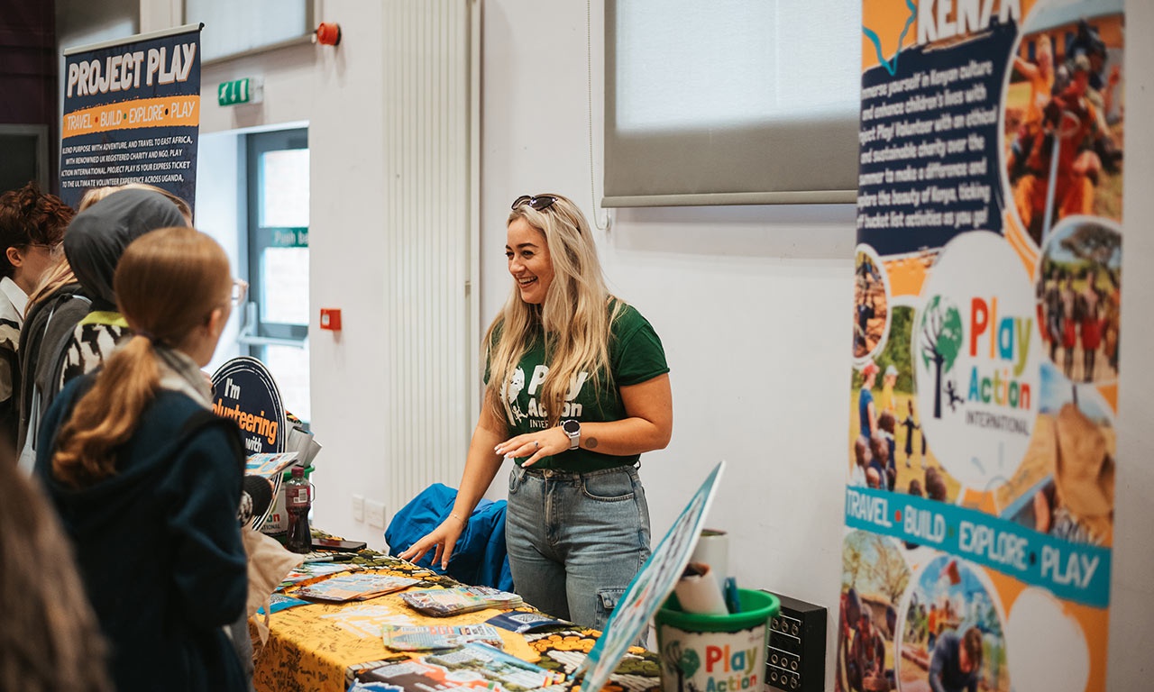 Representative talking to students at Project Play stand at Global Opportunities Fair 