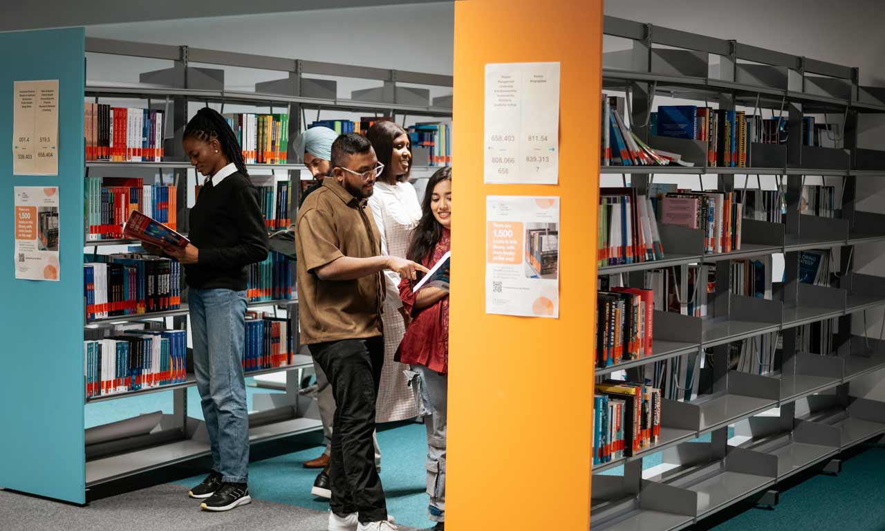 Students reading books in the London Campus library area. 