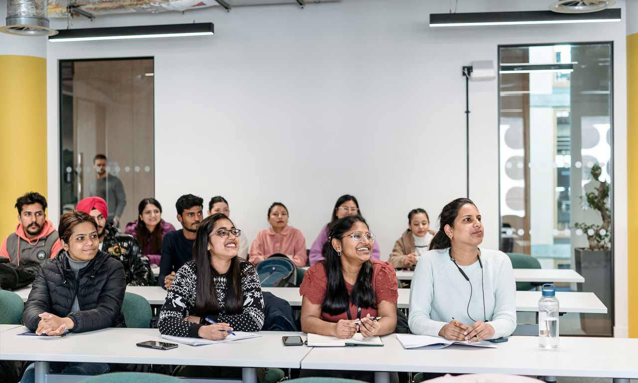 Students listening to a tutor in a London Campus teaching room. 