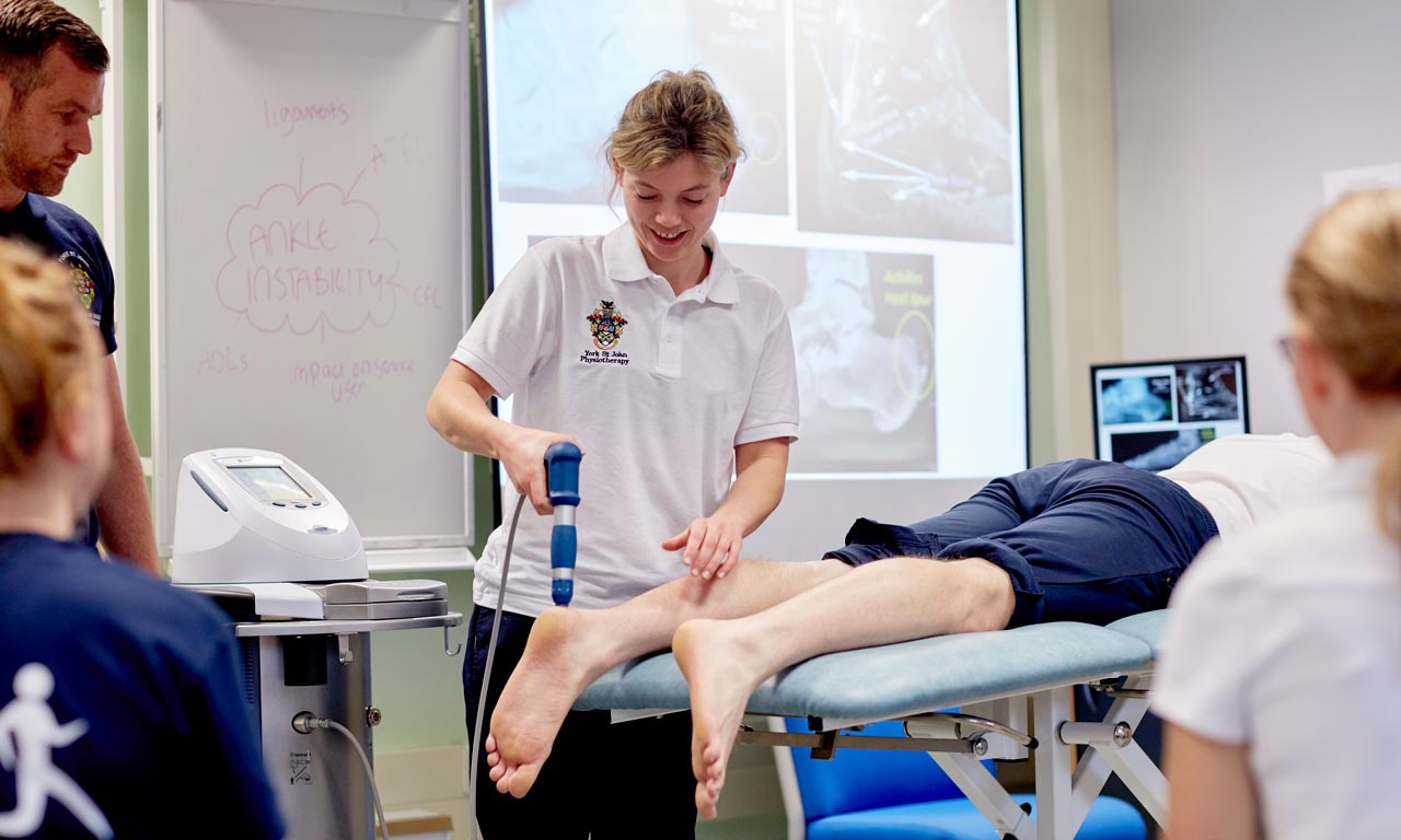 Student using ultrasound machine on patient ankle 