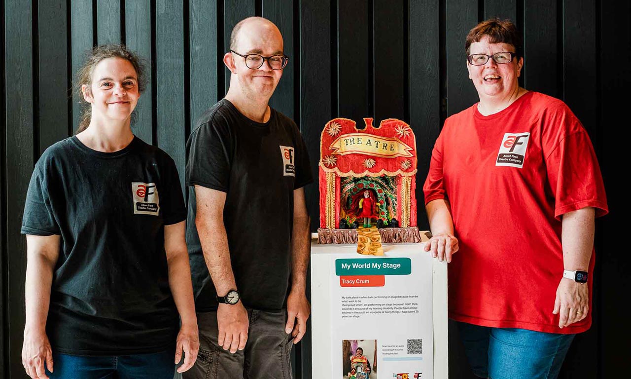 Artists stand next to work, a miniature theatre 