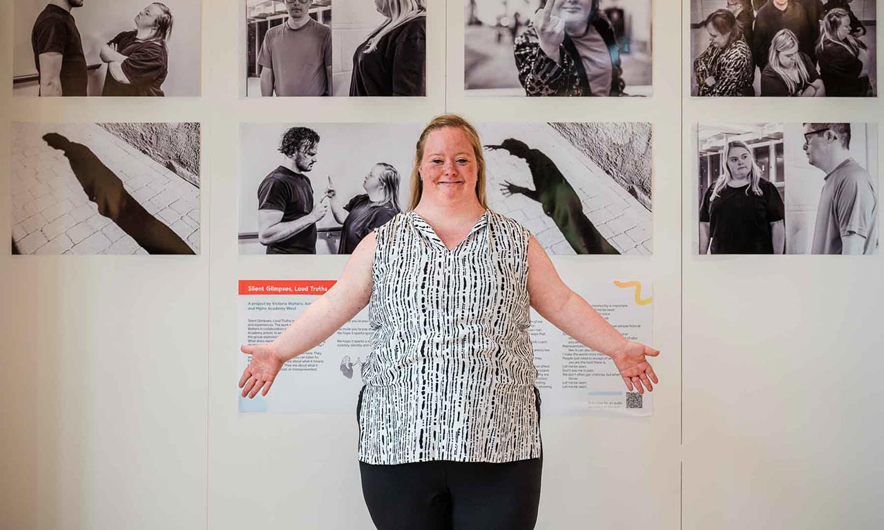 An artist stands in front of photos on a wall 