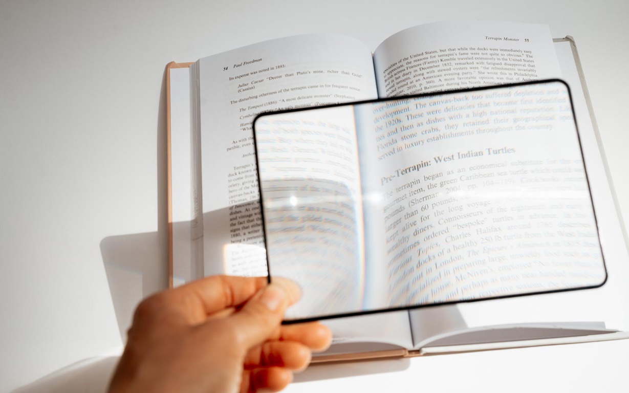 A magnifying sheet being used to enlarge the text in a book. 