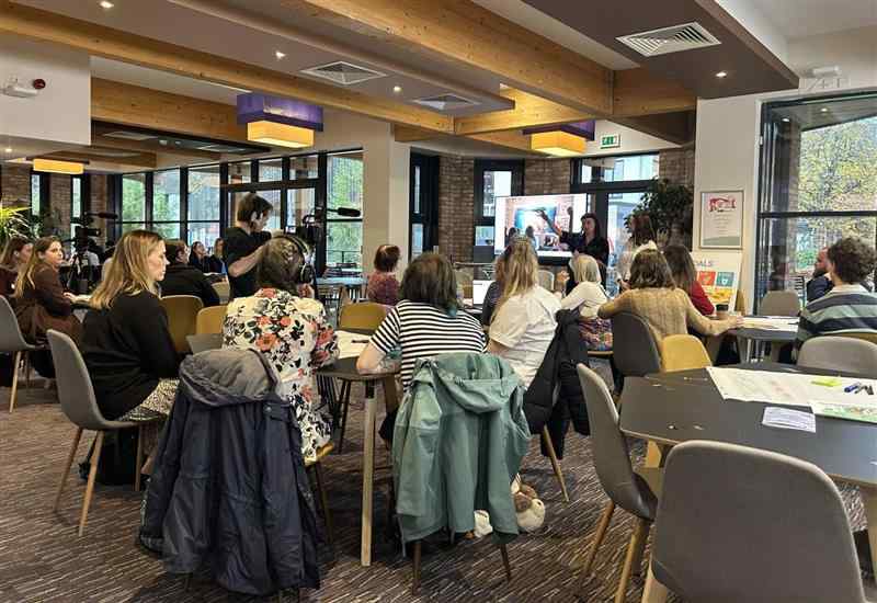 Students present sustainability work to a crowd sitting at tables 