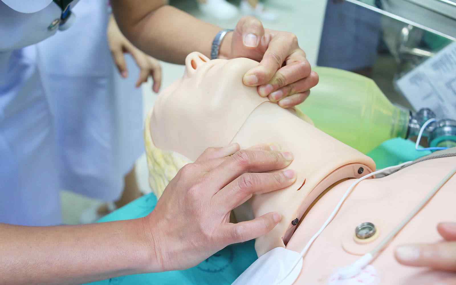 Close up of a student practising technique on an anatomical model of a human neck and head. 